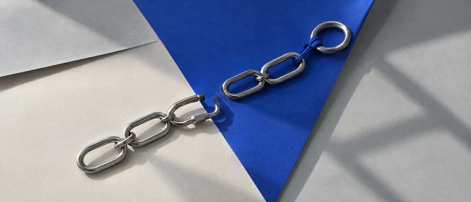 A steel chain lying in two pieces, its fourth link left open.